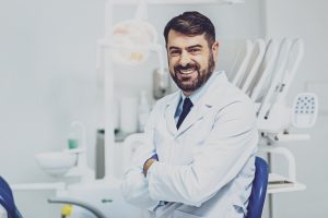 Positive delighted dentist sitting at his workplace