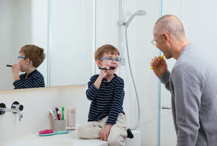 father and son brushing teeth in washroom